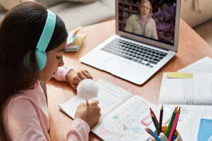 Girl with headphones on participating in online tutoring