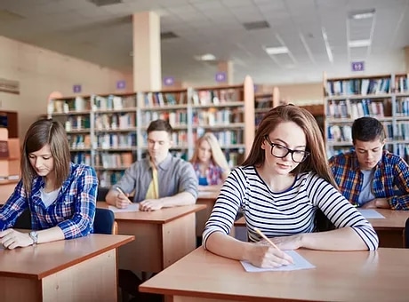 High school students in a library taking standardized tests like SAT, ACT and IEE