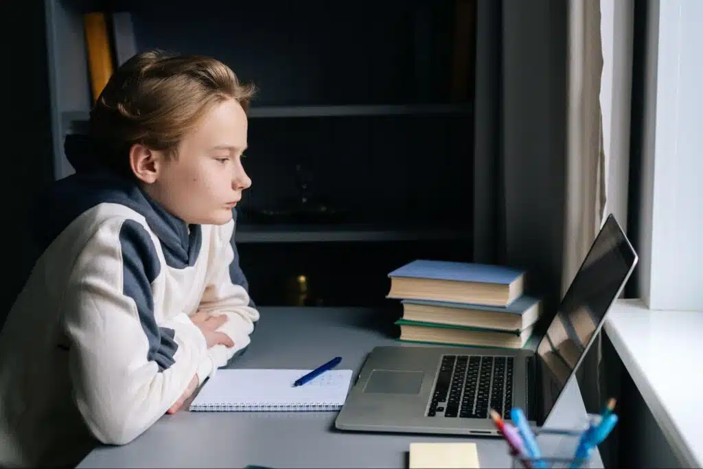 Side view of a young boy looking at a laptop while studying at home