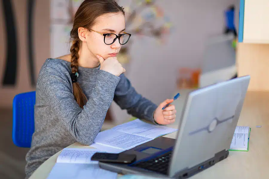 Student working at home with a laptop and class notes